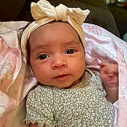 Jayda is registered to the contest to win money with this photo: baby, infant, headband, bow, blanket, soft_toy, stuffed_animal, face, portrait, cute, clothing, patterned_clothing, pink, green, closeup, expression, indoor, cozy, child, newborn