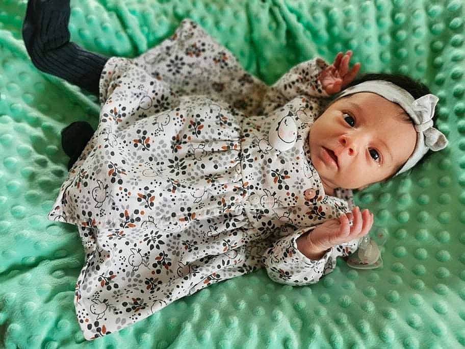 Mya a rejoint le concours — aidez-le/la à gagner de superbes lots ! art, baby, baby_toddler_clothing, close_up, creative_arts, dress, eye, fawn, grass, happy, headwear, leaf, linens, organism, outerwear, pattern, person, sleeve, toddler, wood