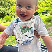 Reese joined the competition — help win amazing prizes! baby, bib, child, clothing, cute, daylight, dinosaur, eyes, face, grass, greenery, hands, happy, holding, infant, nature, outdoor, park, person, smiling
