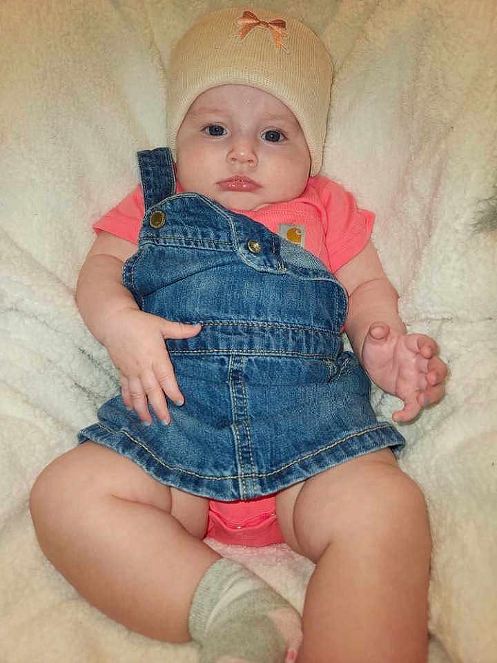 Oaklynn is registered to the contest to win money with this photo: baby, infant, child, denim, overall, hat, beige, pink, blanket, soft, cute, face, skin, hand, foot, sock, clothing, portrait, lying_down, indoor