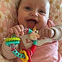 Zélya a rejoint le concours — aidez-le/la à gagner de superbes lots ! baby, child, smile, teething_toy, toy, blanket, pink, daisy_pattern, onesie, hand, face, mouth_open, portrait, cute, cheerful, playful, close_up, pacifier, infant, sleepwear