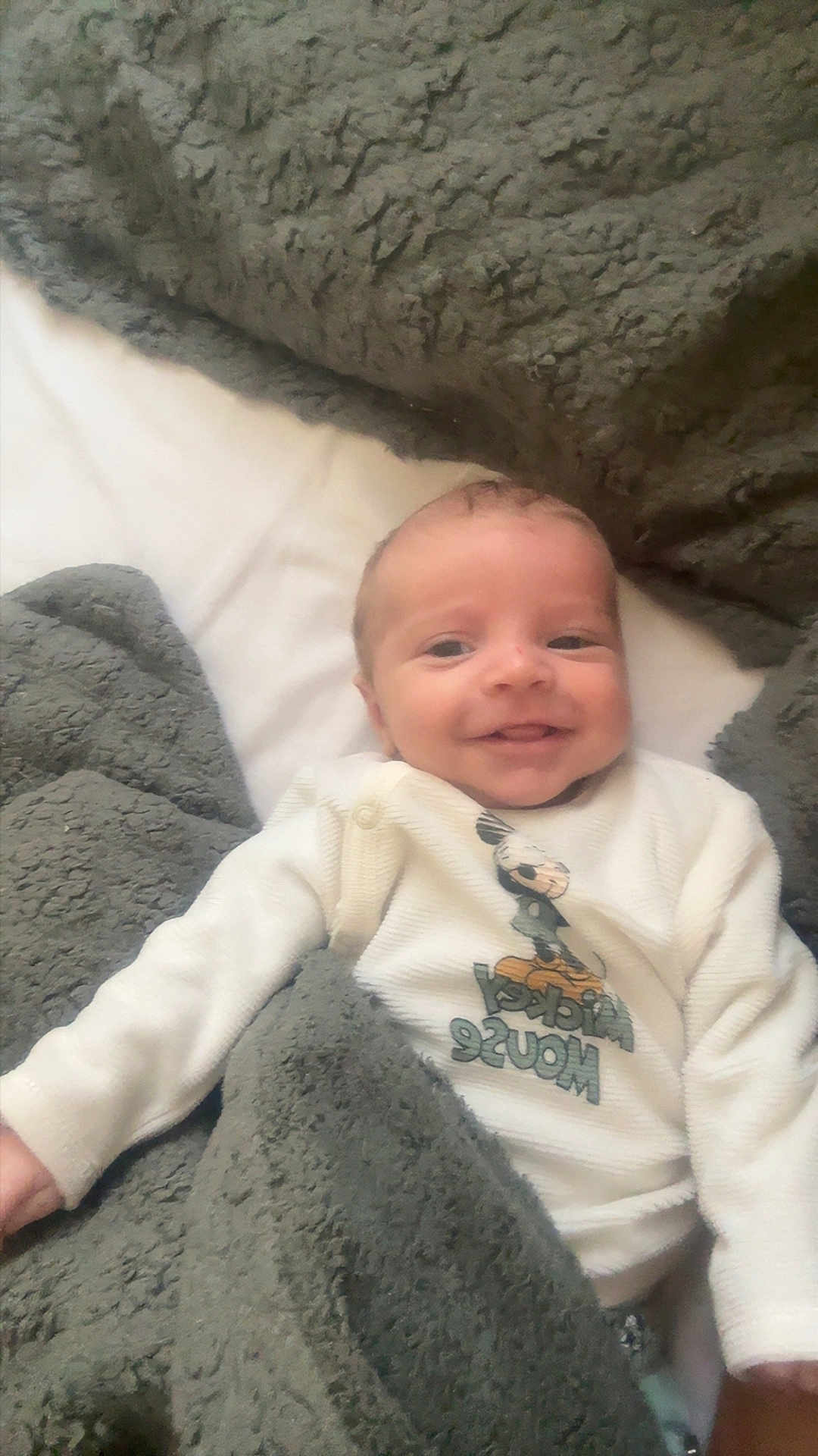 Kayden participe au concours pour gagner de l'argent avec cette photo : baby, infant, smiling, blanket, bedding, cozy_blanket, onesie, mickey_mouse, face, head, newborn, portrait, lying_down, arm, cute, soft_texture, indoor, mattress, sleepwear, happy