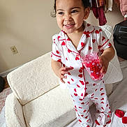 Gia joined the competition — help win amazing prizes! child, toddler, pajamas, hearts, smile, cup, candies, plush_chair, indoor, room, standing, rose_petals, bare_feet, clothing, portrait, happy, furniture, earrings, wall_outlet, bedspread