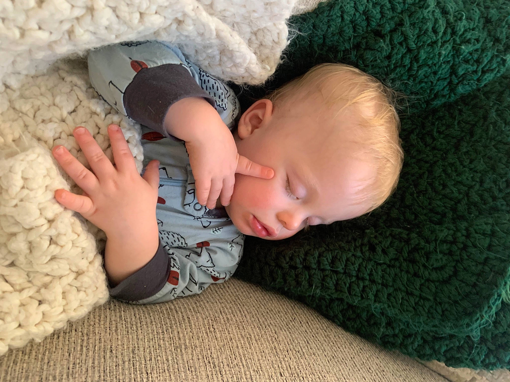 Seamus joined the competition — help win amazing prizes! baby, baby_sleeping, baby_toddler_clothing, child, comfort, finger, flooring, grass, knit_cap, linens, mammal, nail, pattern, person, sitting, skin, sleeve, toddler, vertebrate, wood