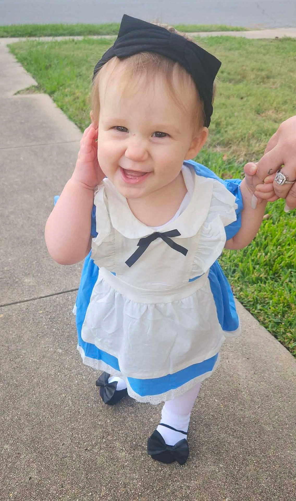 Alyena joined the competition — help win amazing prizes! black_bow, black_shoes, casual, child, cute, daylight, dress, grass, happy, headband, holding_hand, outdoor, person, portrait, sidewalk, smiling, toddler, walking, white_tights, young_child