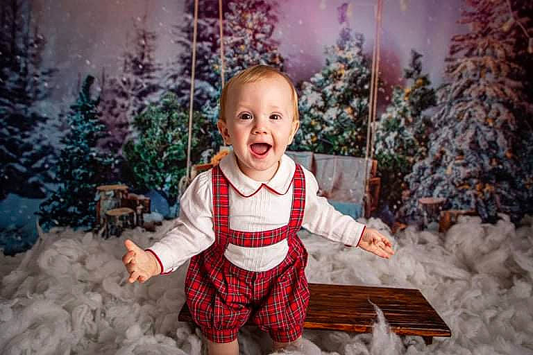 Arthur is registered to the contest to win money with this photo: baby_toddler_clothing, christmas_ornament, christmas_tree, facial_expression, flash_photography, grass, happy, head, leaf, light, lighting, outerwear, people_in_nature, person, photograph, plant, smile, standing, toddler, tree