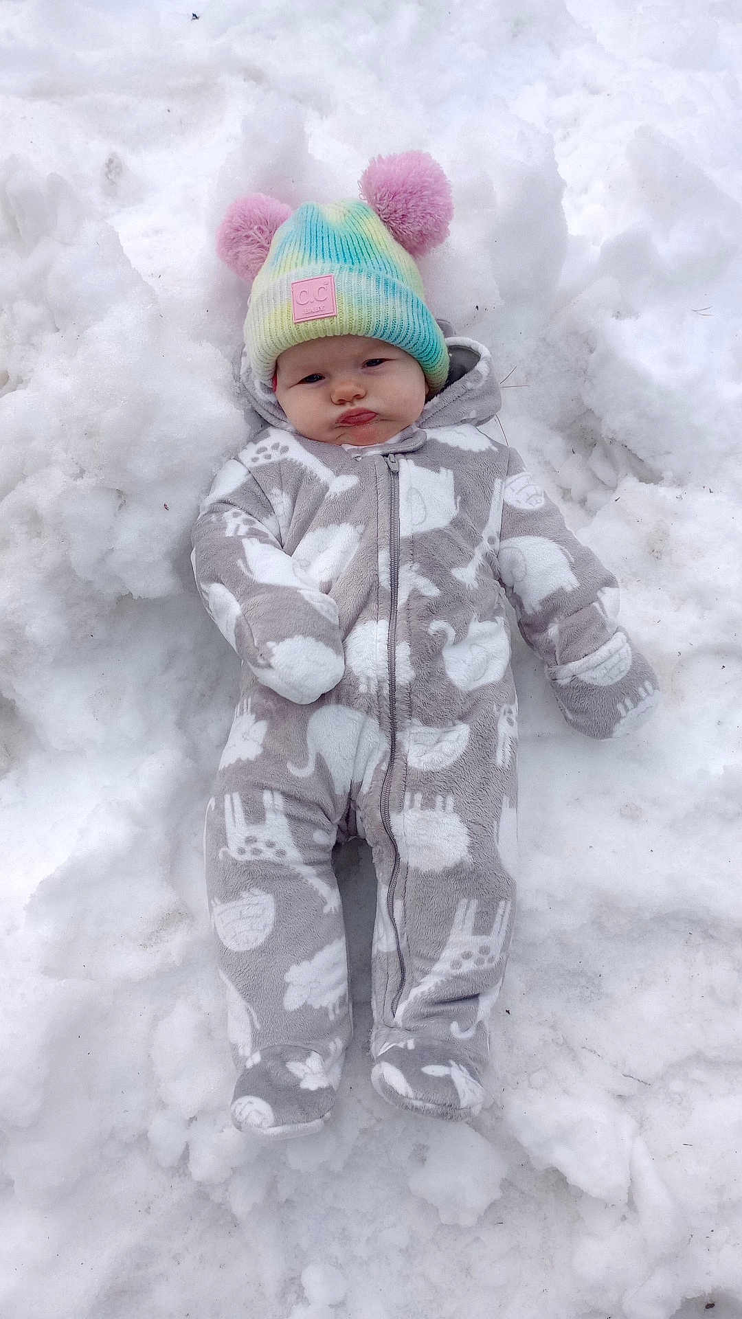 Raven joined the competition — help win amazing prizes! baby, infant, snow, snowbank, beanie, pom_poms, colorful_hat, onesie, animal_print, zipper, bundled, cold_weather, outdoor, portrait, face, cheeks, cute, cozy, winter_clothing, lying_down