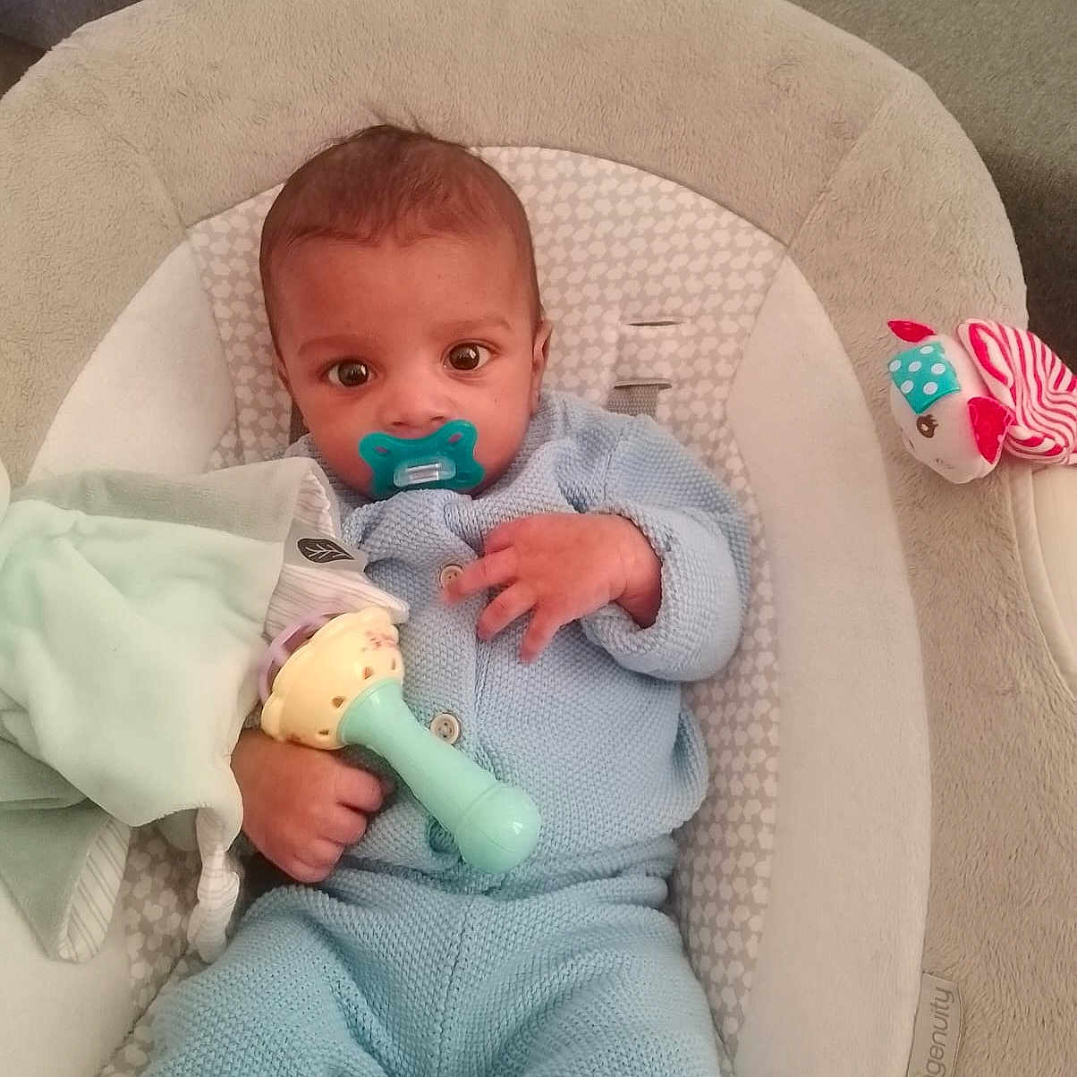 Keïys participe au concours pour gagner de l'argent avec cette photo : baby, big_eyes, blanket, blue_clothing, bouncer_seat, calm, carpet, child, cute, hand, indoor, infant, knitted_outfit, looking_at_camera, pacifier, portrait, rattle, seated, soft_fabric, toy