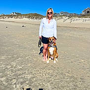 Bodhi is registered to the contest to win money with this photo: woman, dog, beach, sand, sunny, blue_sky, sunglasses, smiling, outdoor, pet, happy, casual_clothing, footwear_off, leash, dunes, residential_houses, daytime, shadow, nature, vacation