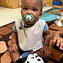 toddler, pacifier, plush_toy, carpet, indoor, child, sitting, bib, striped_clothing, hand, toy, classroom, furniture, floor, play, cute, baby, expression, young_child, person