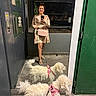 companion_animals, curly_fur, dog, doorway, dress, fluffy, hallway, handbag, indoor, leash, mirror_selfie, person, pet, pink_harness, portrait, reflection, shoes, two_dogs, white_dog, woman