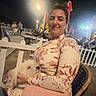 Stella participe au concours pour gagner de l'argent avec cette photo : woman, person, dog, small_dog, fluffy_dog, pet, animal, seated, smiling, portrait, outdoor, night, cafe, restaurant, seaside, flags, chairs, table, floral_clothing, vacation