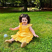Eva joined the competition — help win amazing prizes! child, toddler, yellow_dress, curly_hair, grass, outdoor, sunlight, smiling, happy, nature, greenery, sitting, playful, tree, park, daylight, cute, person, footwear, flower_clip