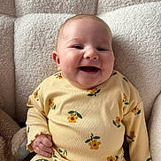 Flora joined the competition — help win amazing prizes! armchair, baby, casual_clothing, child, comfort, cozy, cute, expression, floral_pattern, happy, indoors, infant, person, portrait, seated, smiling, soft_texture, warm_lighting, yellow_outfit, young_child