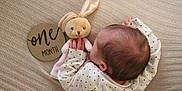 Madelyne is registered to the contest to win money with this photo: baby, one_month, newborn, plush_toy, bunny, blanket, polka_dot_clothing, hand, head, hair, texture, wooden_sign, milestone, infant, soft_toy, sleepwear, cuddly, cute, child, resting