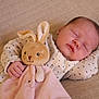 baby, sleeping, plush_toy, bunny, pajamas, polka_dots, hand, blanket, cozy, cute, infant, peaceful, soft, child, resting, cuddling, bedtime, comfort, indoors, portrait