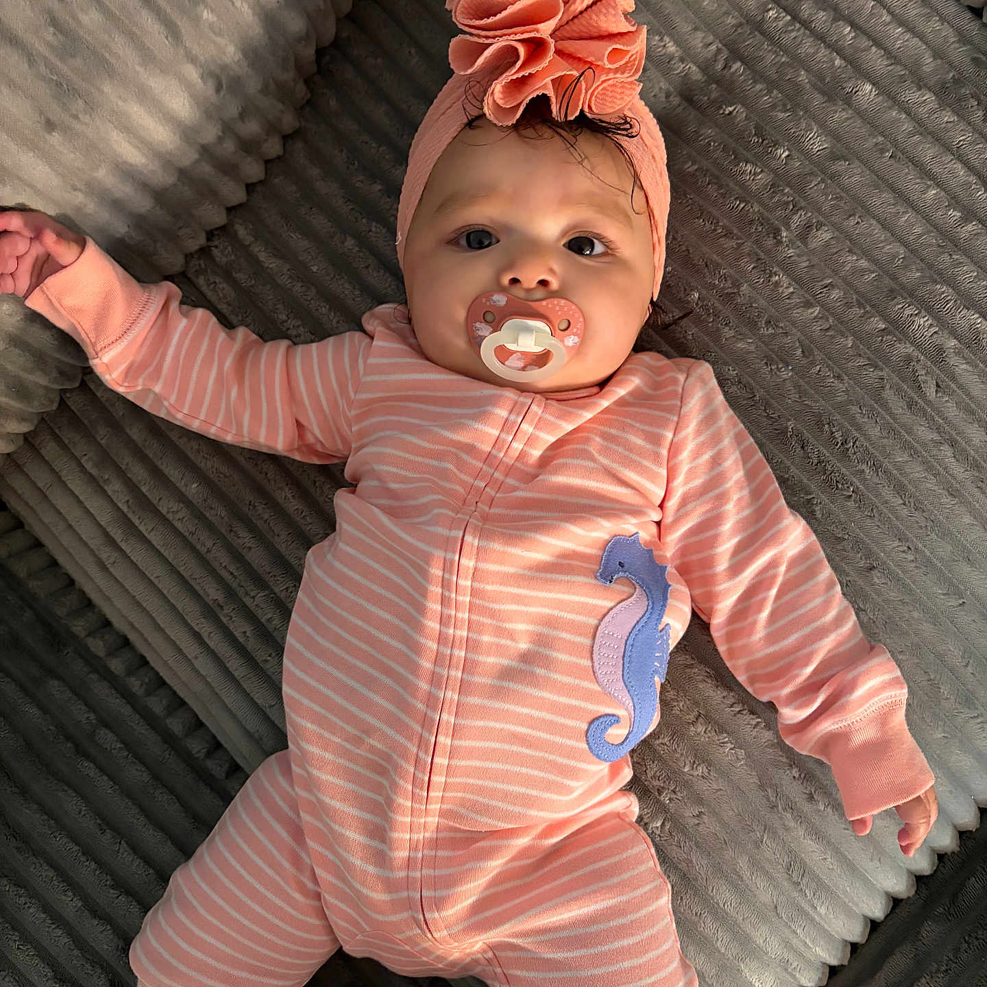 Aleya is registered to the contest to win money with this photo: baby, infant, pink_onesie, headwrap, pacifier, seahorse_patch, lying_down, textured_surface, cute, child, portrait, soft_lighting, indoors, clothing, baby_fashion, sleepwear, adorable, young_child, headwear, cozy