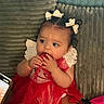 Aleya is registered to the contest to win money with this photo: baby, child, dress, red_dress, bows, sitting, couch, curious, cute, indoors, person, infant, hand, face, smiling, texture, phone, photography, white_bows, playful
