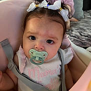 Aleya is registered to the contest to win money with this photo: baby, pacifier, bow, hair, infant, child, seat, pink, clothing, face, expression, indoor, couch, blurred_background, person, cute, soft_lighting, closeup, young_child, domestic