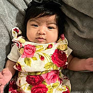 Areli is registered to the contest to win money with this photo: baby, infant, child, face, headband, bow, floral_dress, red_roses, pink_roses, blanket, cozy, cute, portrait, skin, hands, eyes, indoor, apparel, soft_texture, lying_down