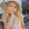 blonde_hair, blue_eyes, bracelet, child, close_up, colorful_clothing, deck, dress, girl, house, long_hair, outdoor, outdoor_furniture, patio, portrait, seated, smiling, straw_hat, summer, sunhat