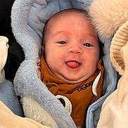 Maëlysse a rejoint le concours — aidez-le/la à gagner de superbes lots ! baby, infant, face, tongue, blue_hood, blanket, clothing, closeup, cute, warm, soft_texture, smiling, person, newborn, child, indoors, portrait, happy, babywear, cozy