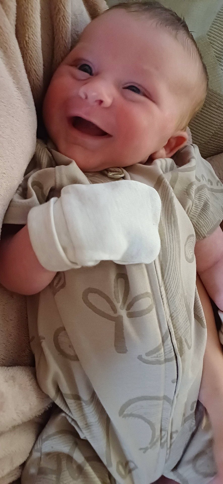 baby, blanket, closeup, comfort, cozy, cute, face, happy, indoor, infant, lying_down, mittens, newborn, patterned_clothing, peaceful, person, skin, small_hand, smiling, soft_texture