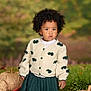 toddler, child, afro, cardigan, bow, green_skirt, autumn, pumpkin, woven_pumpkin, plant, outdoor, curious, portrait, fall, nature, cute, fashion, person, seasonal, leaf