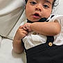Maddox is registered to the contest to win money with this photo: baby, black_clothing, button, child, closeup, couch, curly_hair, cute, expression, face, hand, indoors, infant, leather, person, portrait, sitting, skin, white_clothing, young_child
