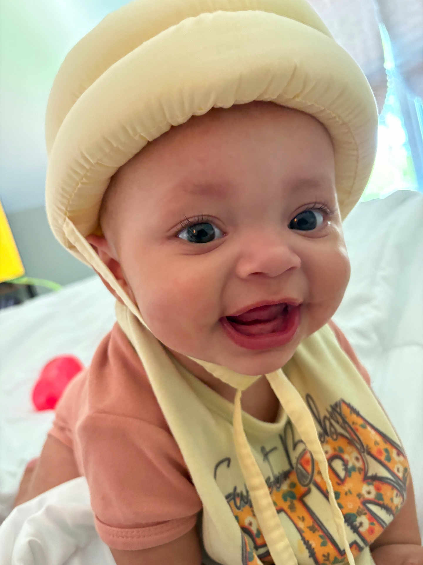Amariah joined the competition — help win amazing prizes! baby, smiling, helmet, bib, indoor, happy, child, face, closeup, apparel, person, cute, infant, expression, clothing, headgear, young, portrait, babywear, babyface