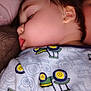 Malcolm is registered to the contest to win money with this photo: baby, sleeping, close_up, face, child, cheeks, hair, clothing, pattern, tractor, cozy, blanket, cushion, soft, peaceful, portrait, indoor, resting, infant, young