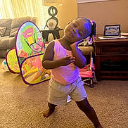 Kassidy joined the competition — help win amazing prizes! toddler, child, indoor, living_room, carpet, play_tent, barney, furniture, lamp, table, sofa, curtains, hair_braids, pink_shirt, shorts, barefoot, smile, pose, toy, home