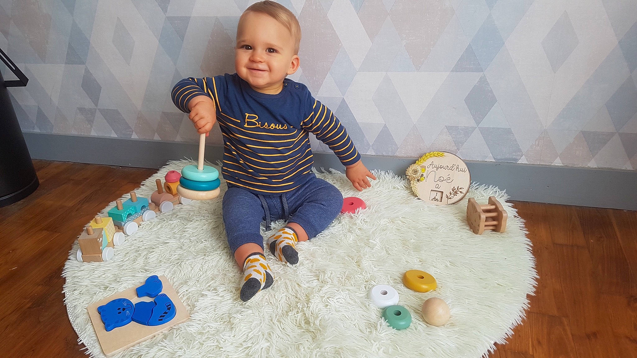 Noé participe au concours pour gagner de l'argent avec cette photo : baby, baby_toddler_clothing, baby_toys, child, event, floor, flooring, fun, joy, leisure, pattern, person, play, product, room, sharing, sitting, sleeve, smile, t_shirt