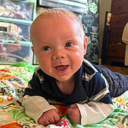 Carter is registered to the contest to win money with this photo: baby, child, infant, smiling, happy, crawling, portrait, close_up, face, eyes, indoor, bedroom, blanket, colorful, clothing, striped_shirt, long_sleeves, furniture, storage_bins, home
