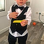 child, toddler, boy, tuxedo, bow_tie, vest, white_shirt, black_pants, barefoot, indoors, wooden_floor, window, orange_ball, electrical_outlets, curious_expression, holding_object, standing, person, clothing, floor
