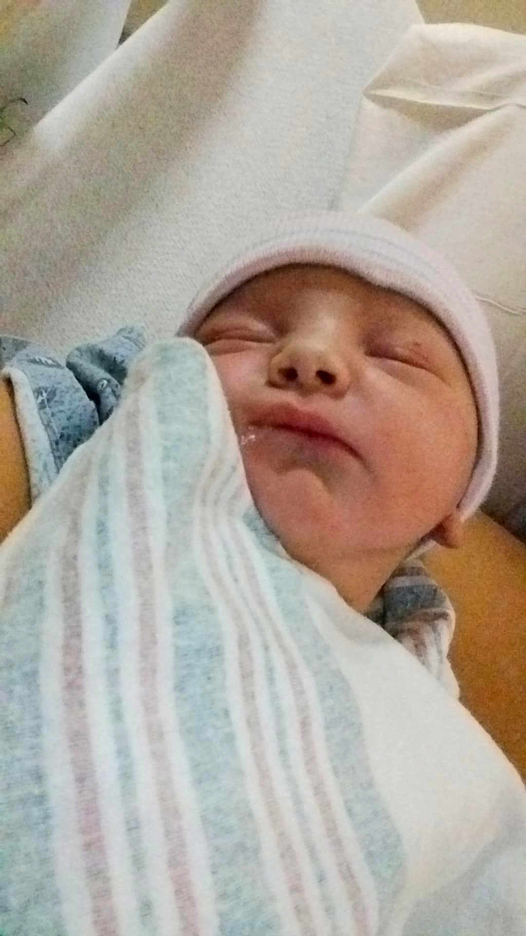 Harley is registered to the contest to win money with this photo: newborn, baby, sleeping, swaddled, blanket, hat, infant, closeup, resting, cozy, soft, peaceful, person, face, skin, human, child, portrait, indoors, sleep