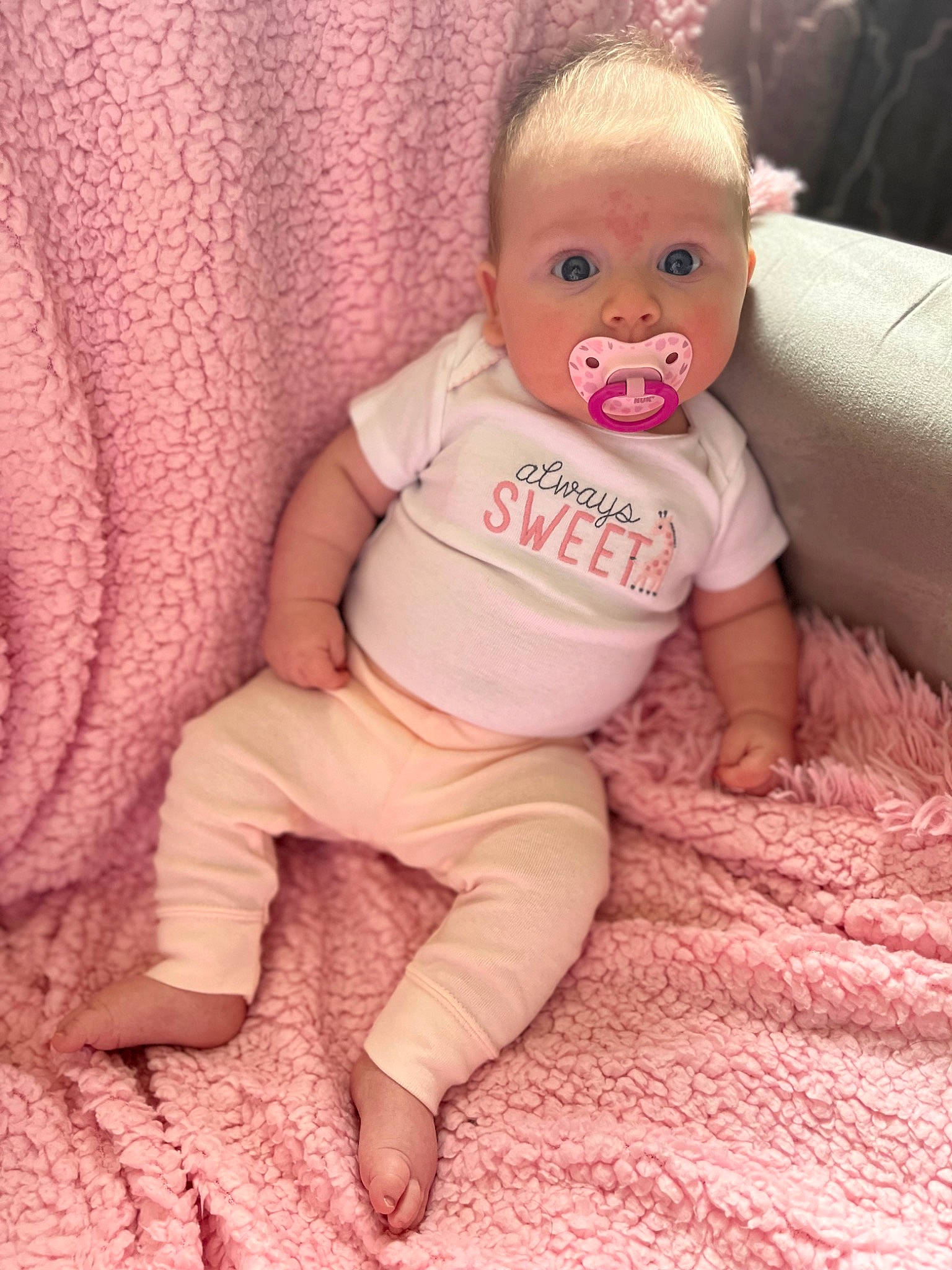 Emmy is registered to the contest to win money with this photo: arm, baby, baby_toddler_clothing, cheek, comfort, eye, face, finger, hand, head, human_body, iris, leg, lip, neck, nose, person, pink, skin, sleeve