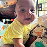 baby, bedroom, blanket, child, close_up, face, happy, home, indoors, infant, pacifier, plush_toy, portrait, sitting, smiling, sunlight, television, toy, window, yellow_outfit