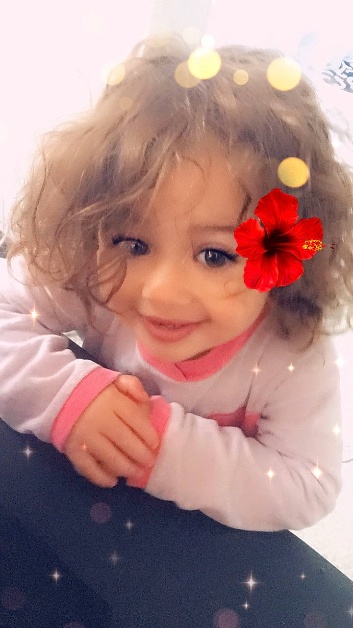 Ilyana participe au concours pour gagner de l'argent avec cette photo : baby, cheek, child, face, flower, hair_accessory, head, joy, person, petal, pink, plant, smile, toddler