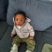 Syncere joined the competition — help win amazing prizes! toddler, child, couch, clothing, hoodie, pants, sneakers, footwear, curly_hair, indoor, furniture, seated, young_child, expression, face, person, textile, cushion, blanket, casual_wear