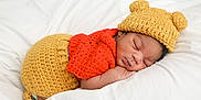 Syncere is registered to the contest to win money with this photo: newborn, baby, sleeping, crocheted_clothing, yellow_hat, orange_top, soft_bedding, cozy, cute, infant, portrait, peaceful, child, sleep, knitwear, headwear, resting, baby_clothes, toddler, indoor