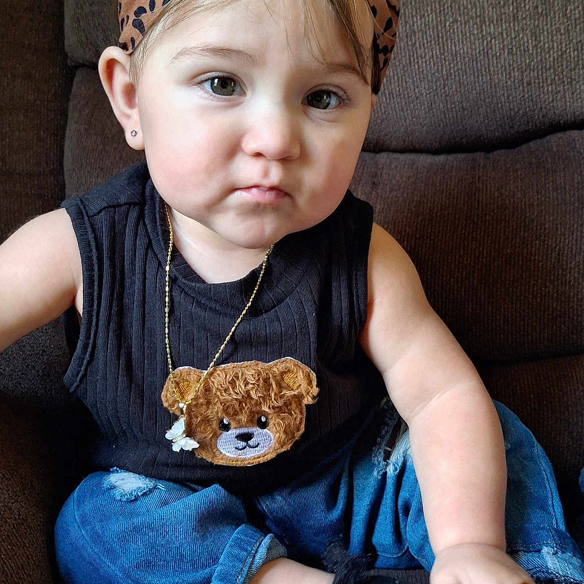 Natalie is registered to the contest to win money with this photo: accessory, baby, black_top, child, couch, cute, earrings, expression, fashion, feet, hand, headband, indoor, jeans, portrait, sitting, socks, teddy_bear, toddler, young_child