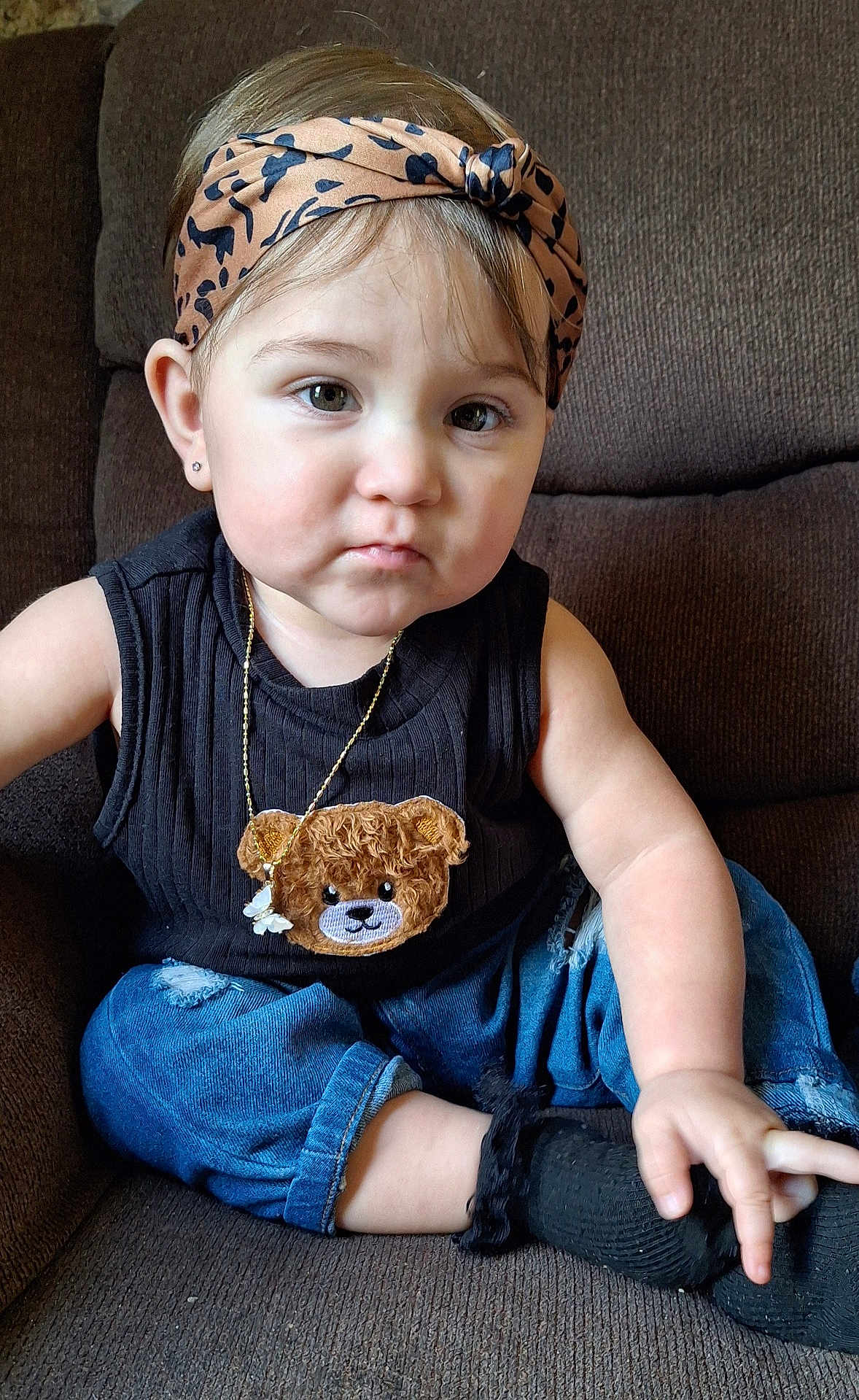Natalie is registered to the contest to win money with this photo: toddler, child, baby, headband, black_top, teddy_bear, jeans, socks, couch, indoor, portrait, sitting, cute, fashion, accessory, earrings, expression, hand, feet, young_child