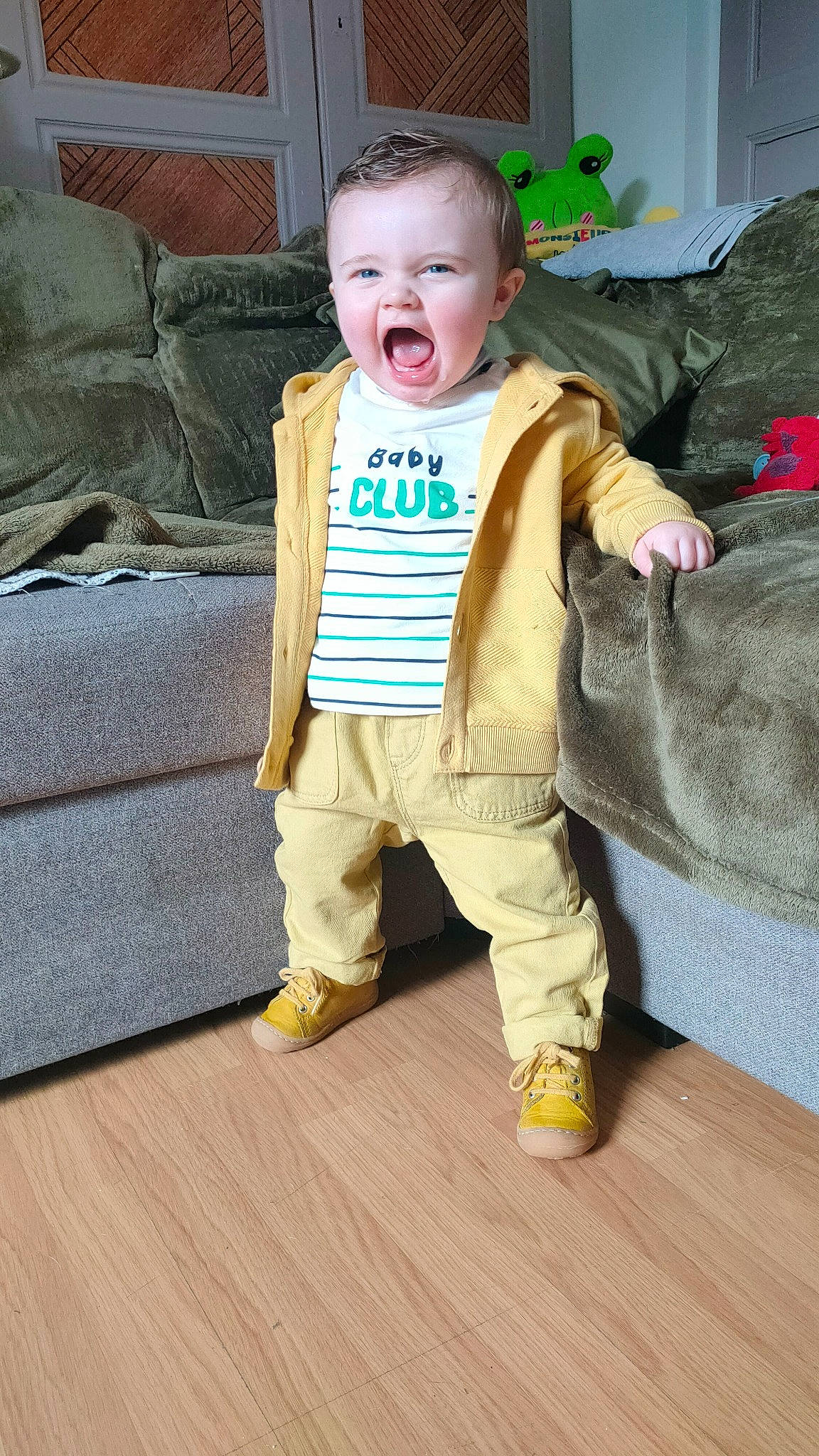 Hélän a rejoint le concours — aidez-le/la à gagner de superbes lots ! baby, baby_toddler_clothing, child, comfort, couch, eye, floor, flooring, happy, hardwood, linens, person, room, sleeve, smile, stuffed_toy, t_shirt, toddler, wood, wood_flooring