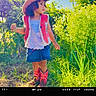 child, cowboy_hat, vest, denim_skirt, boots, outdoor, grass, plants, sunny, nature, portrait, curly_hair, greenery, blue_sky, standing, daylight, fashion, casual, young, person
