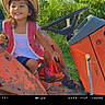 child, girl, cowboy_hat, pink_vest, boots, tractor, rusty, outdoor, greenery, grass, smile, happy, sunlight, nature, playful, farm, vehicle, seat, hand, young
