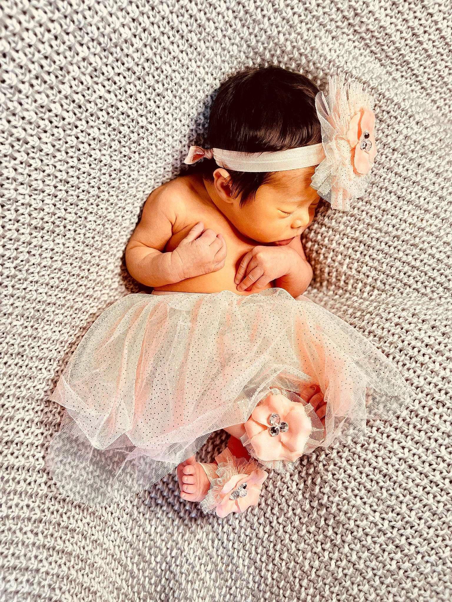 Averi is registered to the contest to win money with this photo: baby, baby_toddler_clothing, barefoot, cap, child, doll, dress, flooring, foot, happy, headpiece, human_leg, jewellery, leg, pattern, peach, person, petal, pink, skin