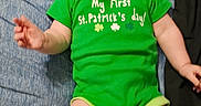 Eve joined the competition — help win amazing prizes! baby, bed, blue_sheet, child, chubby_legs, clothing, cute, face, green_clothing, hair, hands, happy, indoor, infant, laughing, lying_down, onesie, portrait, smiling, st_patrick