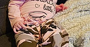 Eve joined the competition — help win amazing prizes! baby, blanket, camo_pants, casual, child, cozy, cute, furniture, home, indoor, infant, person, pink_clothing, portrait, pout, seated, socks, sofa, soft, young