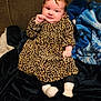 baby, blanket, child, couch, cozy, cute, dress, face, furniture, happy, head, home, indoor, infant, leopard_print, person, plush, sitting, smile, socks